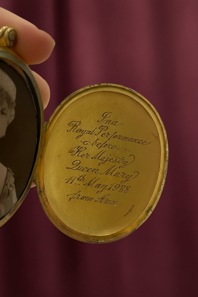 Close-up of an antique gold locket with engraved text.